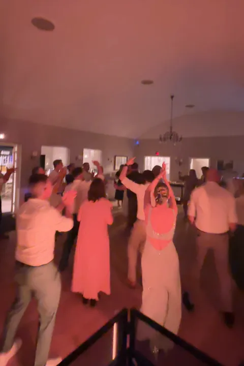 Bruden danser med armene i vejret på et fyldt dansegulv